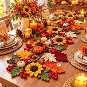 Op de afbeelding: Een lange, decoratieve herfsttafelloper met gehaakte zonnebloemen, esdoornbladeren in rood-, oranje- en geeltinten, kleine witte pompoenen en trossen rode bessen, uitgestald op een houten tafel met kaarsen.