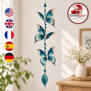 May include: A vertical hanging decoration featuring three crocheted butterflies in shades of teal, blue, and white, attached to a central twisted cord. The piece ends with a crocheted leaf-shaped pendant and includes small round beads.