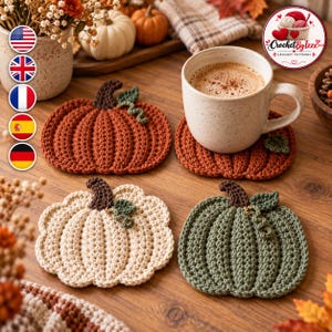 Puede incluir: Tres posavasos de ganchillo con forma de calabaza en color naranja quemado, crema y verde salvia. Cada posavasos tiene un tallo marrón oscuro y una pequeña hoja verde. Una taza de cerámica moteada con café descansa sobre uno de ellos.