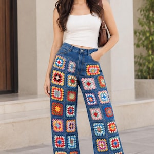 Puede incluir: Vaqueros de mezclilla azul con silueta de pierna ancha y un diseño de patchwork compuesto por cuadrados de ganchillo multicolores. Los pantalones tienen una construcción clásica de cinco bolsillos, cierre de botón y cremallera, y talle alto.