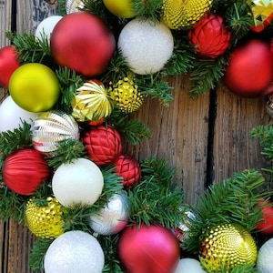 May include: A Christmas wreath with green pine branches and red, white, silver, and gold ornaments.