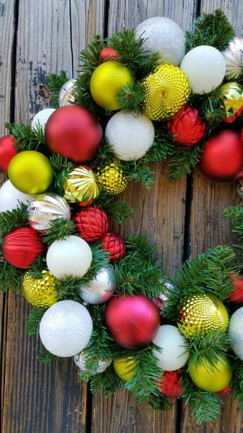 May include: A Christmas wreath with green pine branches and red, white, silver, and gold ornaments.