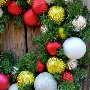 May include: A Christmas wreath with green pine branches and red, white, silver, and gold ornaments.