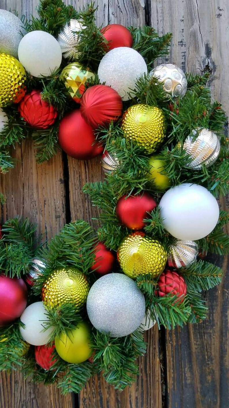 May include: A Christmas wreath with green pine branches and red, white, silver, and gold ornaments.