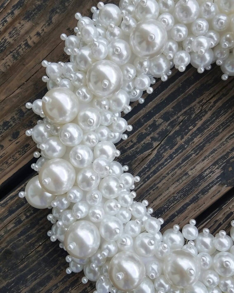 Puede incluir: Una corona de perlas blancas con un gran n&uacute;mero de perlas de diferentes tama&ntilde;os. La corona est&aacute; hecha de perlas falsas y es perfecta para una boda u otra ocasi&oacute;n especial.