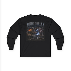Puede incluir: Una camiseta negra de manga larga con un gráfico en la espalda. La imagen muestra a un soldador con casco trabajando en metal, junto a una bandera estadounidense, un camión y el texto "BLUE COLLAR" y "BUILDING A BETTER TOMORROW".