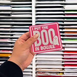May include: A square embroidered patch with a hot pink background and a white border. The text reads I PUT THE BOO IN BOUJEE in white capital letters, with the word BOO featuring a small white ghost graphic integrated into the letter O.