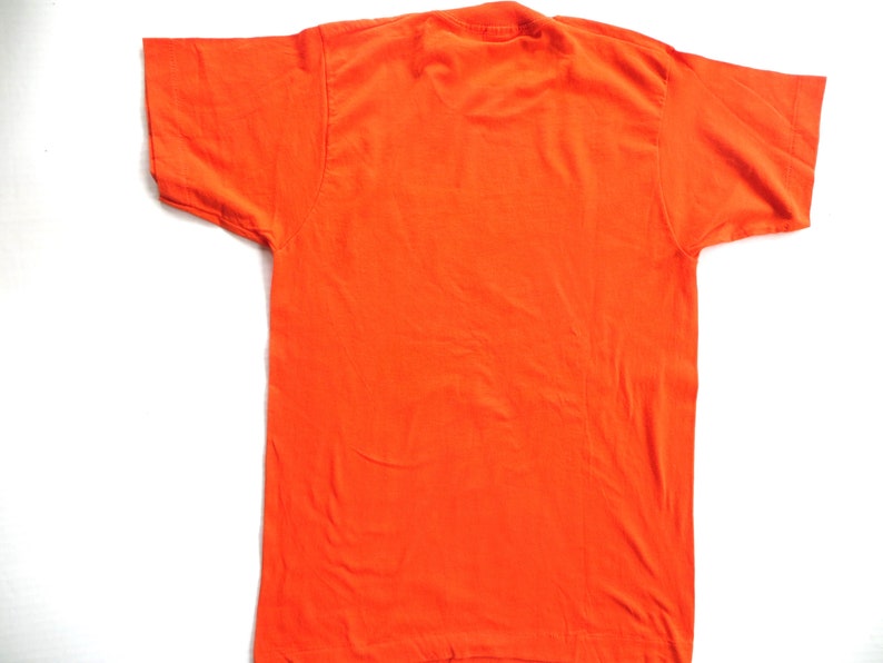 Puede incluir: Una camiseta lisa de color naranja con mangas cortas.