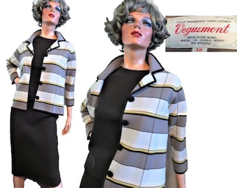 May include: A grey and white striped jacket with black buttons and a black collar. The jacket is made of 100% pure wool and is hand-loomed. The label reads "Voguemont" and "Fully Fashioned - Hand Loomed".