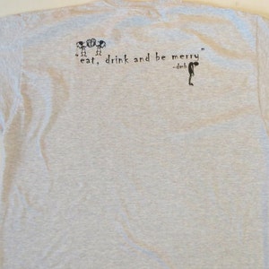 May include: A gray t-shirt with a black graphic print of three stick figures and the text "eat, drink and be merry" -dmb.