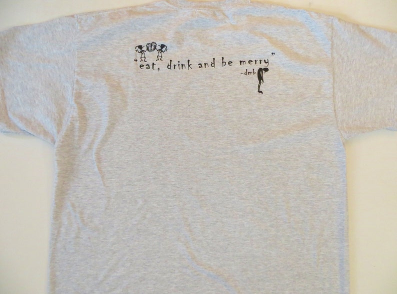 May include: A gray t-shirt with a black graphic print of three stick figures and the text "eat, drink and be merry" -dmb.