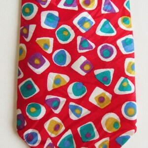 Peut inclure: Cravate en soie rouge avec un motif géométrique de cercles et de triangles blancs, jaunes, bleus et violets.
