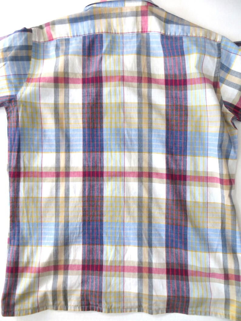 May include: A white button-down shirt with a plaid pattern in shades of blue, yellow, red, and brown.
