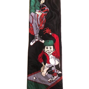 May include: A black silk tie with a cartoon illustration of two golfers. The golfers are wearing red, green, and white clothing. The tie has the word "MAD" printed on the bottom.