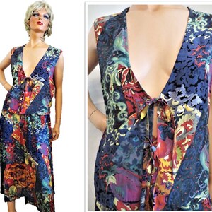 May include: A sleeveless dress with a deep V-neck and a tie at the waist. The dress is made of a colorful patterned fabric with a mix of blue, red, yellow, and green.
