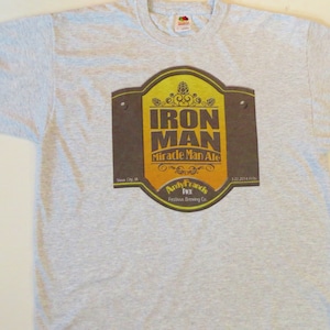 May include: Gray t-shirt with a brown and yellow label that says "Iron Man Miracle Man Ale" and "Andy Franks Festbier Brewing Co."