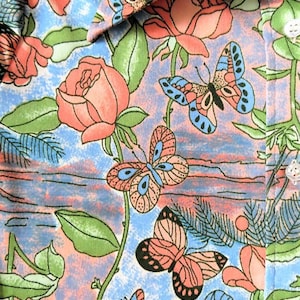K&ouml;nnte beinhalten: Ein blauer und rosa Stoff mit einem Blumenmuster mit Schmetterlingen und Rosen. Der Stoff hat eine strukturierte Oberfl&auml;che und eine Vintage-&Auml;sthetik.