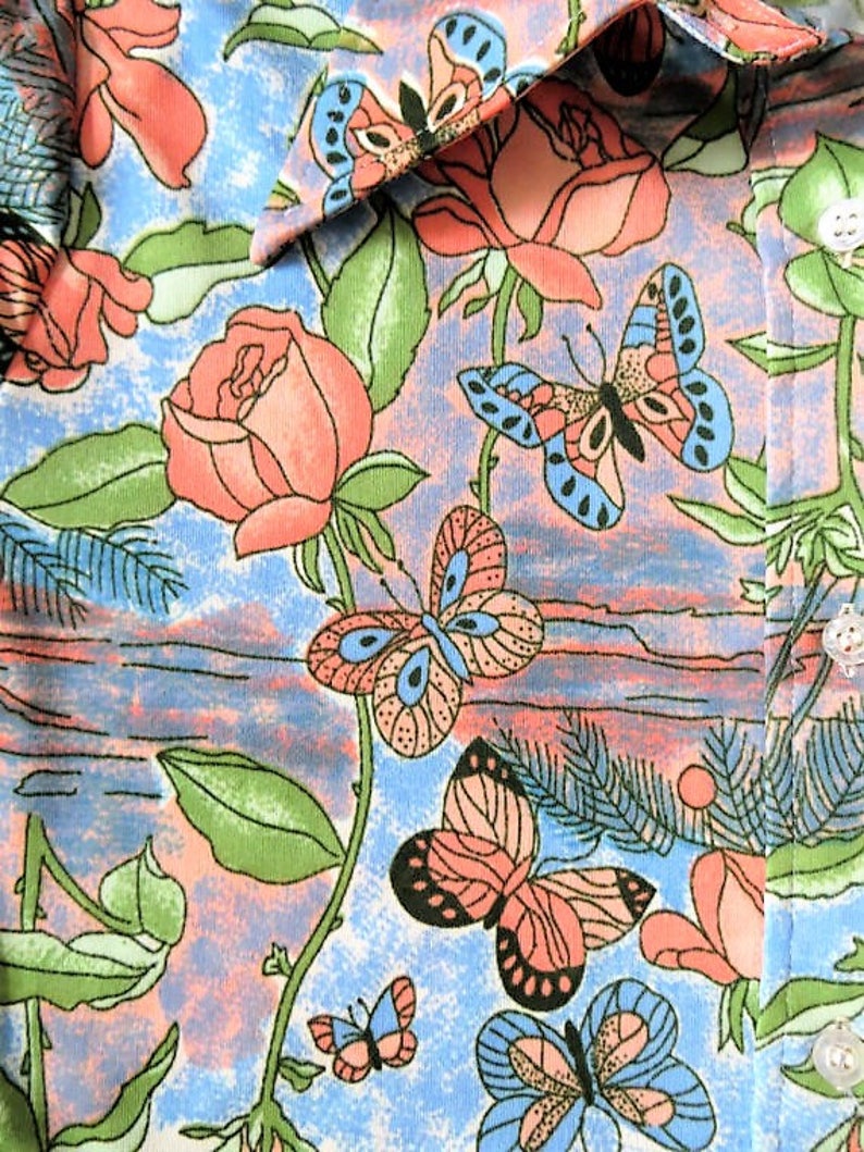 K&ouml;nnte beinhalten: Ein blauer und rosa Stoff mit einem Blumenmuster mit Schmetterlingen und Rosen. Der Stoff hat eine strukturierte Oberfl&auml;che und eine Vintage-&Auml;sthetik.