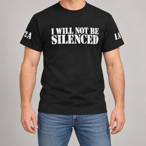 May include: A black short-sleeved t-shirt featuring the white text I WILL NOT BE SILENCED printed across the chest. The sleeves display the white text 2A on the left and 1A on the right, both in a distressed, bold, sans-serif font.