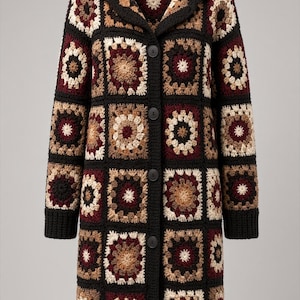 May include: A long-sleeved, hooded cardigan constructed from a patchwork of crocheted granny squares in shades of black, burgundy, tan, and cream. The garment features a solid black crocheted hood, cuffs, and hem, with four black buttons down the front.
