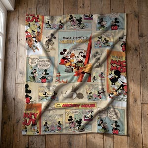 Op de afbeelding: Een rechthoekige plaid met een vintage stripboekprint van Walt Disney's Mickey Mouse. Het ontwerp bevat meerdere panelen met Mickey Mouse in verschillende scènes, tekstballonnen en de vetgedrukte tekst Walt Disney's Mickey Mouse.