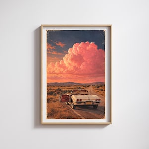 May include: A framed wall art print depicting a vintage white convertible car parked on the shoulder of a desert road. The scene features a dramatic sunset with large, vibrant pink and orange clouds over distant mountains and a number plate reading FLYIN.