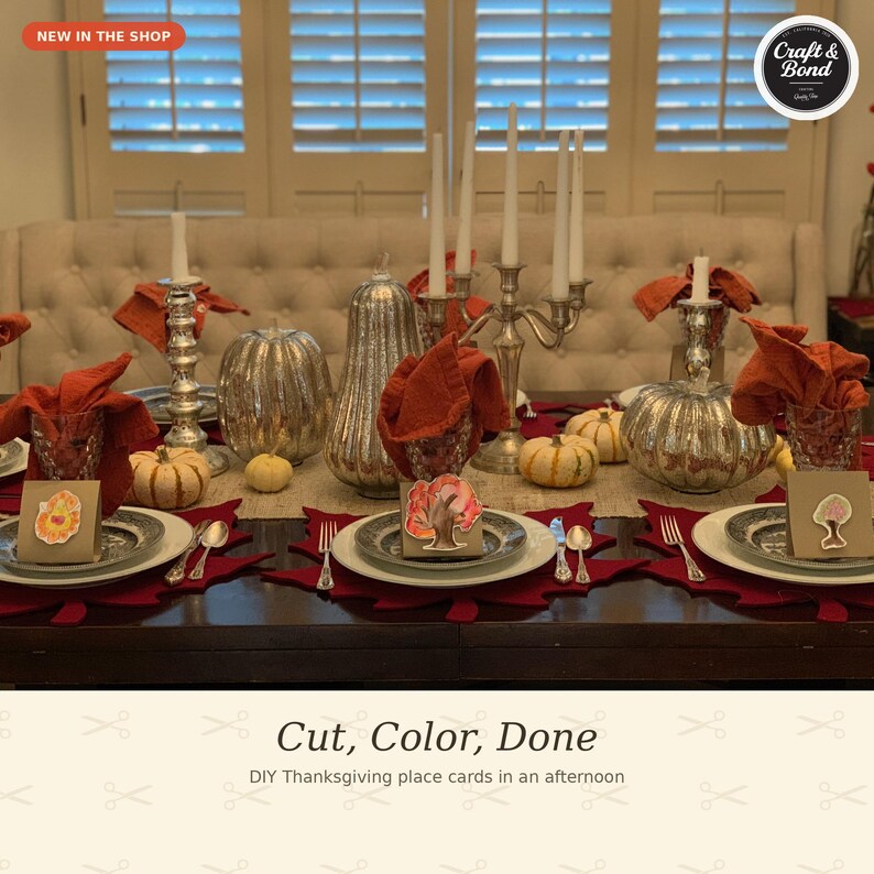May include: A Thanksgiving table setting featuring white plates, red leaf-shaped placemats, and orange napkins. The centerpiece includes silver pumpkins, a tall silver candelabra with white candles, and small paper place cards with tree illustrations.