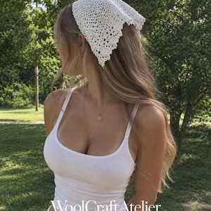 Puede incluir: Un pañuelo triangular de ganchillo blanco con un delicado patrón calado y un borde festoneado, combinado con una camiseta de tirantes blanca acanalada. La imagen incluye el texto WoolCraftAtelier CROCHET PATTERN DESIGN STUDIO en el centro inferior.