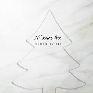 May include: A 10-inch Christmas tree cookie cutter. The metal cutter is in the shape of a stylized evergreen tree. The text "10" xmas tree" and "COOKIE CUTTER" is above the tree outline.