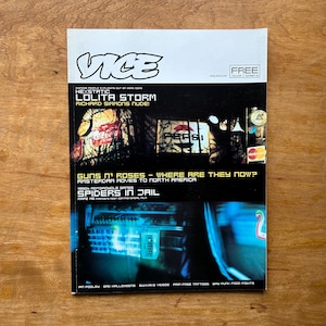 May include: A Vice magazine issue featuring a white header with the Vice logo and the text FREE. The cover displays a dark night scene with illuminated Coca-Cola and Pepsi signs, followed by headlines including Lolita Storm and Spiders in Jail.