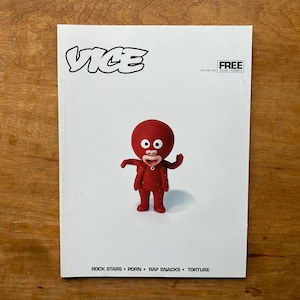 May include: A white magazine cover featuring the black text VICE at the top and the word FREE in a box. In the centre is a red cartoon character with large white eyes and a small mouth. The bottom text reads ROCK STARS • PORN • RAP SNACKS • TORTURE.