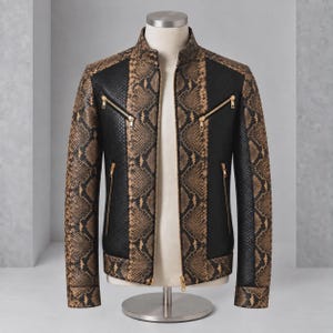 Peut inclure: Une veste présentant un motif peau de serpent marron et noir sur les manches et les panneaux centraux, contrastée par des panneaux latéraux noirs texturés. Le vêtement comprend un col montant, une fermeture éclair frontale et quatre poches zippées dorées.