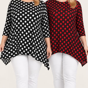 May include: Two long-sleeve tunic tops with an asymmetrical hemline and a round neckline. One top is black with white polka dots, and the other is red with black polka dots. Both tops are paired with plain white trousers.