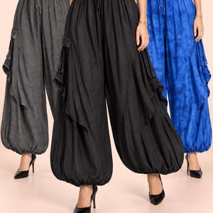 May include: Three pairs of loose-fitting, wide-leg pants with elasticized drawstring waists and gathered, cuffed ankles. The pants feature side cargo pockets with ruffled detailing and are shown in charcoal gray, solid black, and vibrant blue.