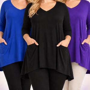 May include: A collection of three v-neck tunics with three-quarter length sleeves and two front pockets. The tunics are shown in solid blue, black, and purple colors, each featuring a high-low hemline and a smooth, lightweight fabric construction.