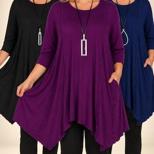 Puede incluir: Una colección de tres túnicas de manga larga en negro, morado y azul marino. Cada túnica presenta un cuello redondo, mangas tres cuartos, bolsillos laterales y un detalle de costura vertical ondulada. Se lleva un collar largo con colgante.
