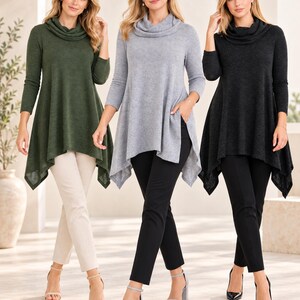 May include: Three cowl neck tunics with long sleeves and asymmetrical hemlines, shown in olive green, light gray, and black. Each tunic features a relaxed fit, side pockets, and a soft-textured knit fabric, paired with slim-fit trousers and heels.