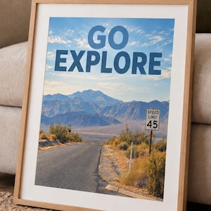 May include: A framed wall art print featuring a desert landscape with a paved road leading toward distant mountains under a blue sky. The text GO EXPLORE is printed in large blue letters at the top, and a speed limit 45 sign stands on the right.