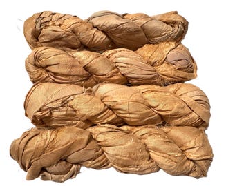 May include: Four bundles of braided, tan-colored silk ribbon. The silk has a slightly wrinkled texture and a natural, earthy tone. The braids are tightly woven, suggesting a durable and versatile material for crafts or embellishments.
