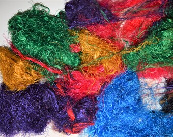 May include: A pile of colorful, shredded fabric in shades of green, red, yellow, blue, and purple. The fabric is soft and fluffy, and it looks like it could be used for crafting or other creative projects.