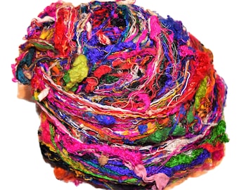 May include: A large ball of colorful silk ribbon yarn. The yarn is a mix of bright colors, including pink, blue, green, red, and yellow. The yarn is tightly wound and appears to be soft and delicate.