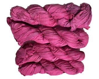May include: A bundle of vibrant pink fabric, tightly twisted and layered. The material appears to be textured, with visible folds and creases. The color is a rich, saturated pink, suggesting a textile product.