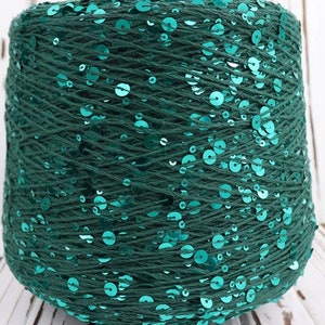 May include: A spool of teal green yarn with sequins woven throughout.