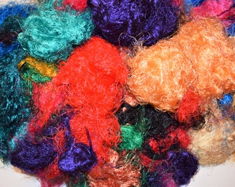 May include: A pile of colorful silk fibers in shades of teal, purple, orange, red, and black. The fibers are soft and fluffy, and they would be perfect for crafting or adding texture to a project.