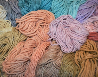 May include: A collection of colorful yarn skeins in various shades of blue, pink, orange, brown, and beige. The yarn is arranged in a circular pattern, with the ends of the skeins overlapping.