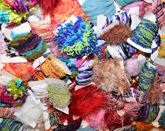 May include: A variety of colorful and textured trims and fringe, including blue, green, red, pink, and white. The trims are arranged in a pile and some are wrapped around white cardboard.