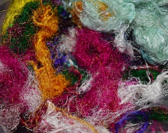 May include: A close-up of a pile of colorful, fluffy yarn scraps in a variety of colors, including pink, green, white, blue, and yellow.