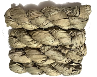 May include: Braided strands of olive green fabric, tightly woven together. The fabric appears to be silk or a similar material, with a slightly shiny finish. The strands are thick and textured, creating a visually interesting pattern.