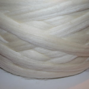 May include: A close-up of a large, white, fluffy ball of yarn. The yarn is tightly wound and has a soft, natural texture.