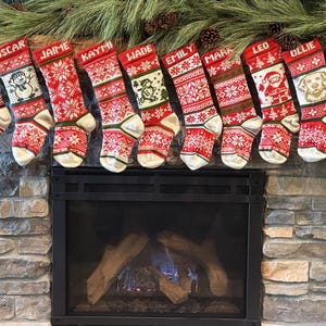 Könnte beinhalten: Eine Reihe von zehn personalisierten Weihnachtsstrümpfen, die in einer Linie hängen. Jeder Strumpf zeigt ein rot-weißes Strickmuster mit einer individuellen Grafik und den Namen Gemma, Oscar, Jaime, Kaymi, Wade, Emily, Mark, Leo, Ollie und Macy.